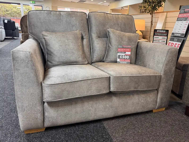 Mink fabric 2 seater sofa with two scatter cushions and wooden feet, with its clearance ticket, in our Blackpool showroom