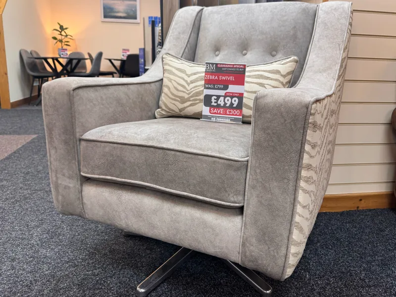 Grey fabric swivel armchair with a zebra-print back and cushion on a chrome swivel base, with its clearance ticket, in our Blackpool showroom
