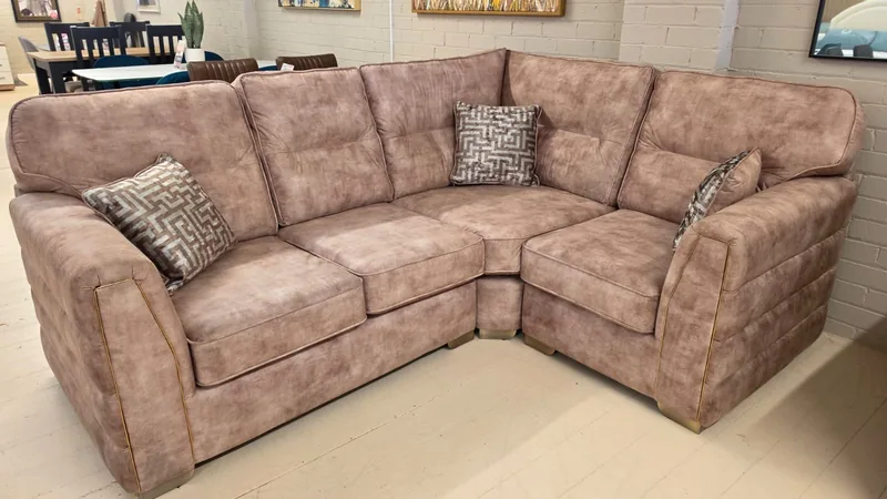 Soft rose fabric corner sofa with scatter cushions and gold-tone accents, in our Cleveleys showroom